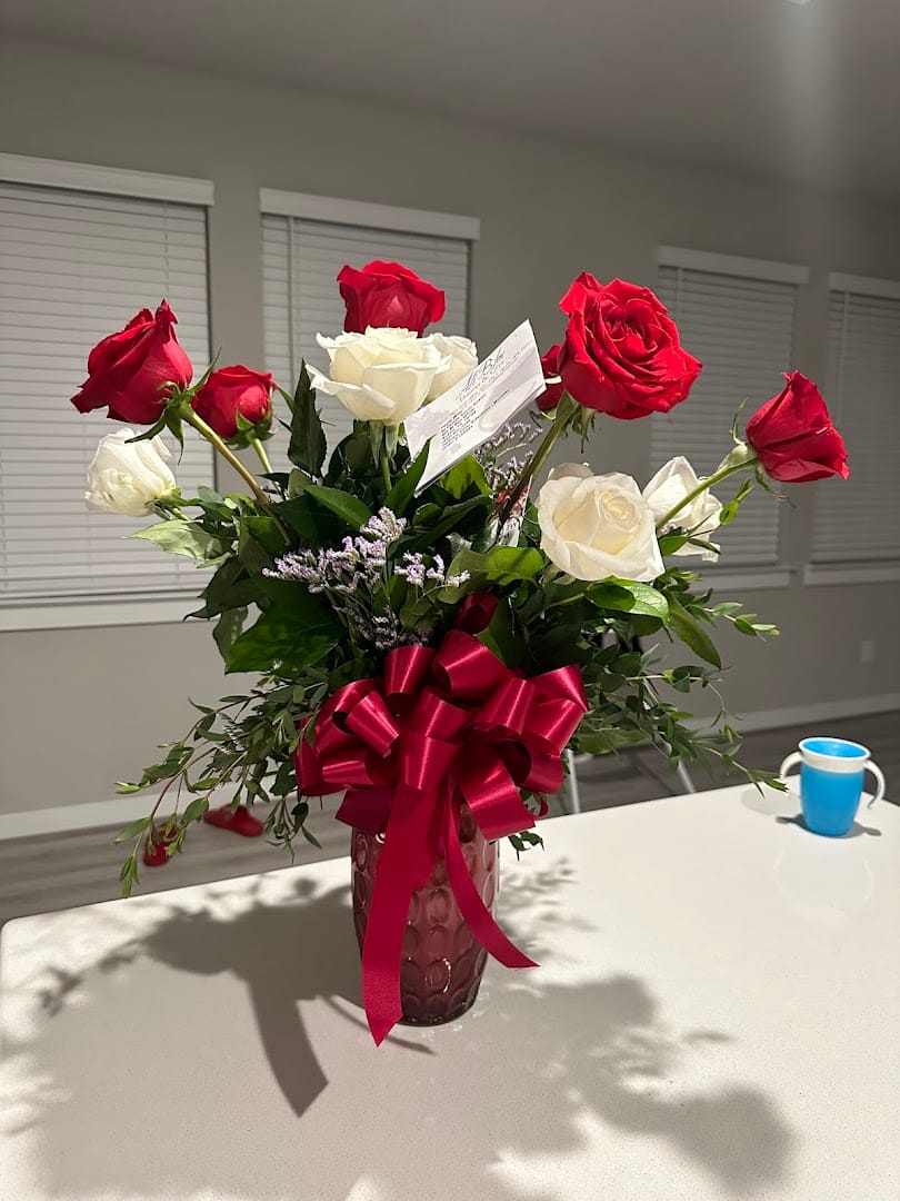 Vase bouquet of red and white roses with a red ribbon
